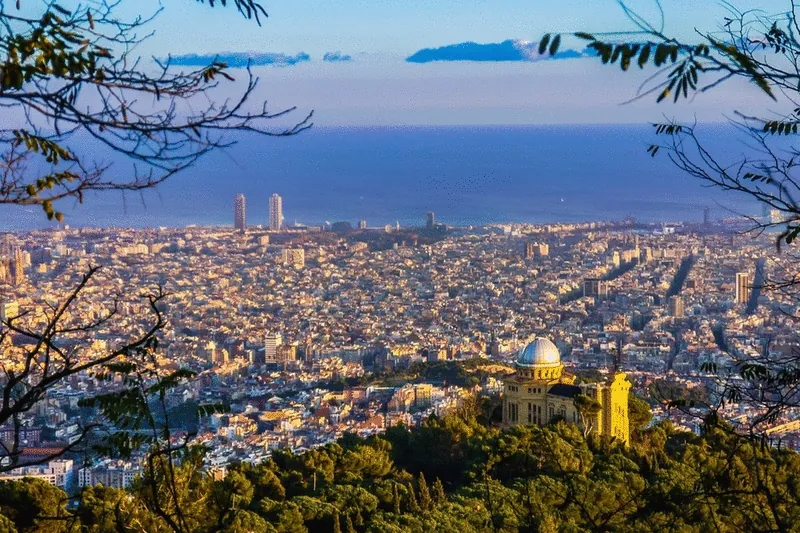 View over Barcelona from the hills to the sea, with a domed observatory among the trees
