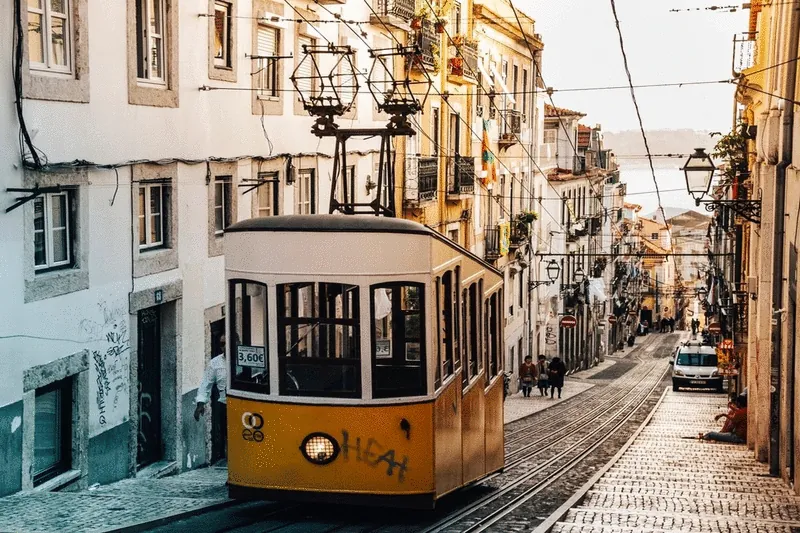 A yellow tram climbing a steep cobbled street in Lisbon
